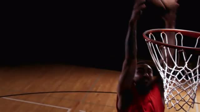 A close up of a basketball player running up and dunking the ball