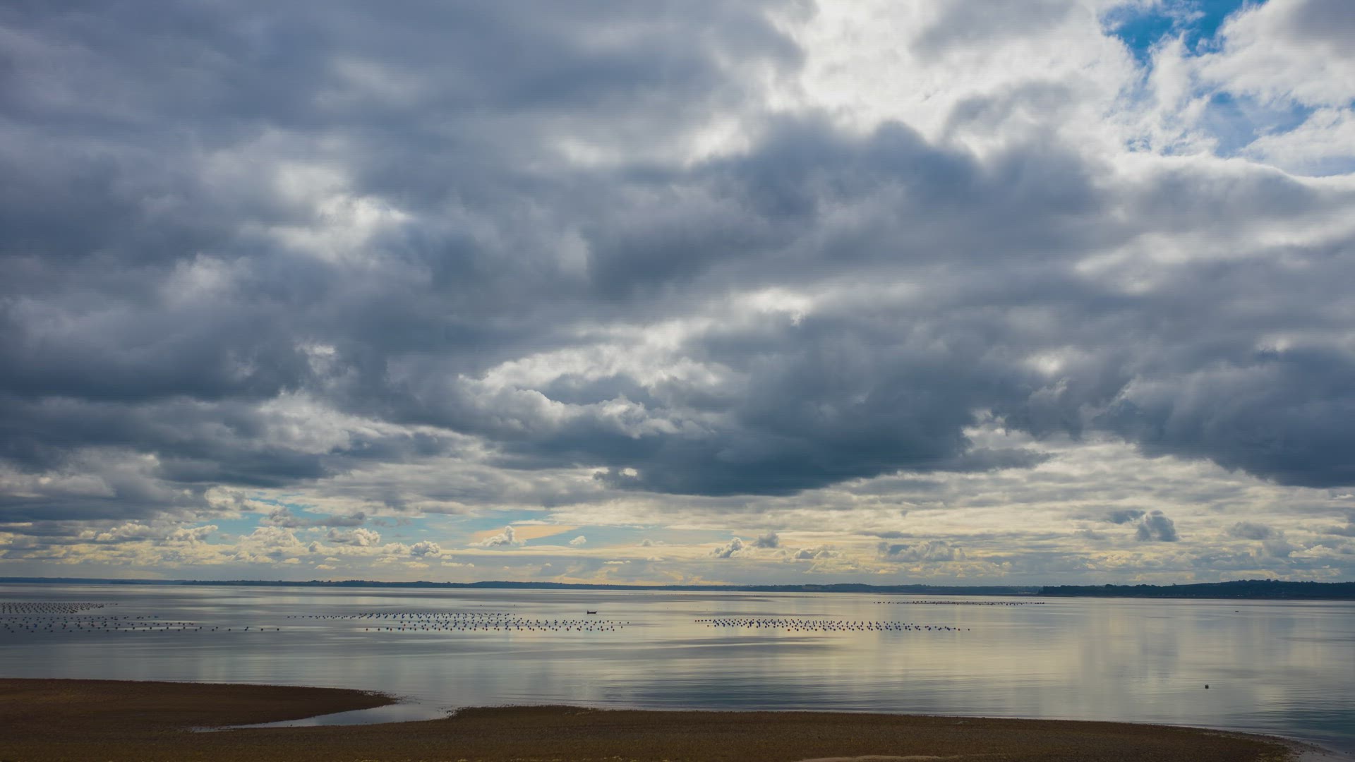 clouds moving above a still ocean, reflection of clouds in the water.