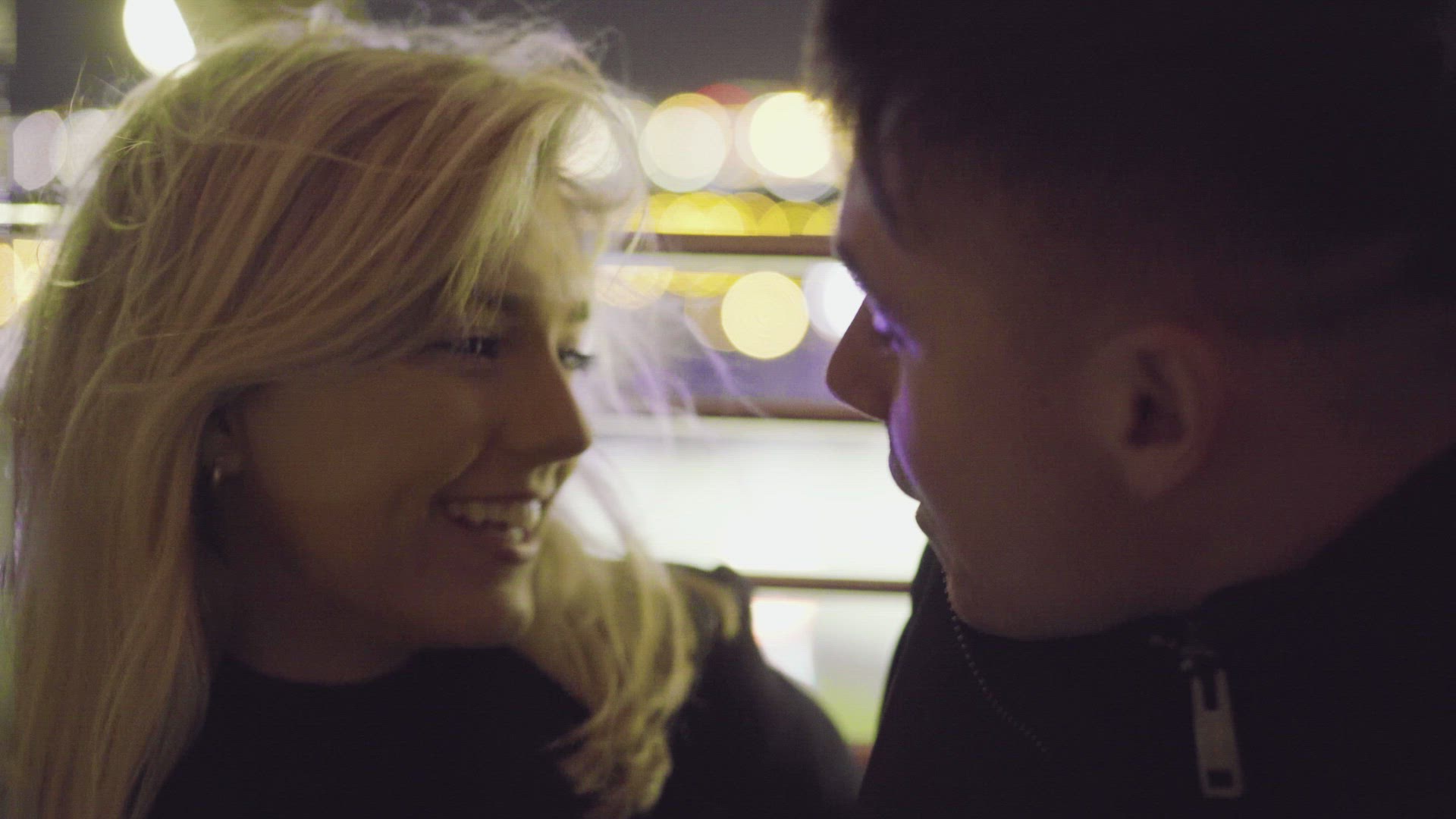 Couple kissing and laughing at amusement park at night, Belfast, Northern Ireland, UK