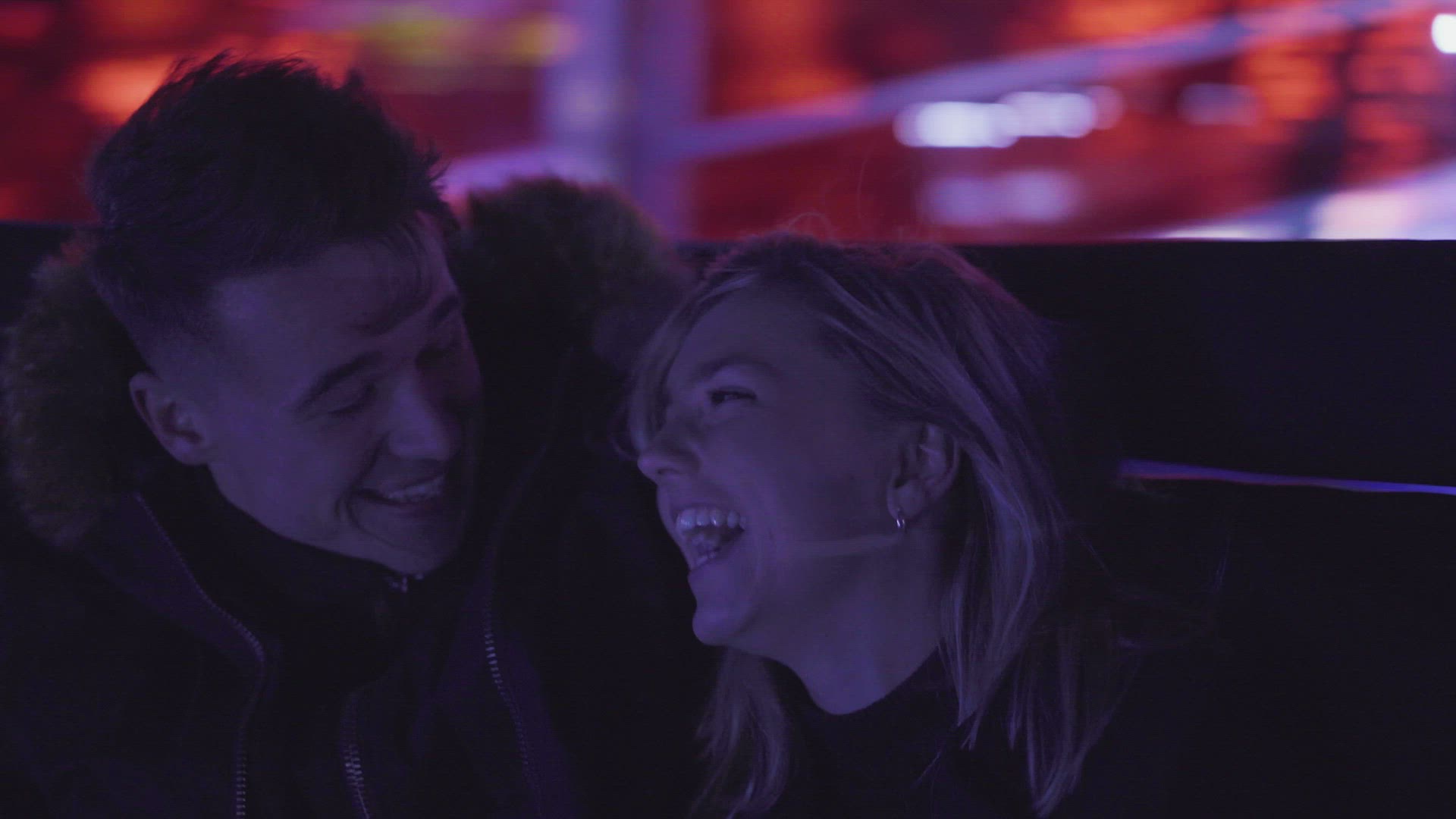 Couple laughing on amusement park ride at night, Belfast, Northern Ireland, UK