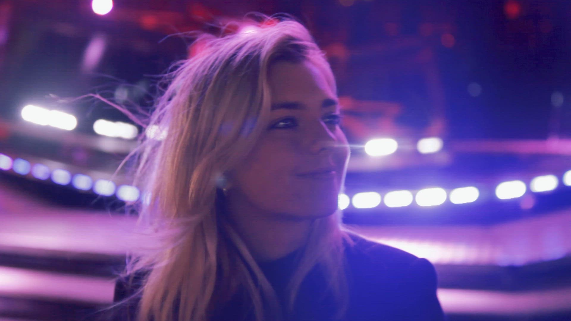 Smiling young woman on amusement park ride at night, Belfast, Northern Ireland, UK