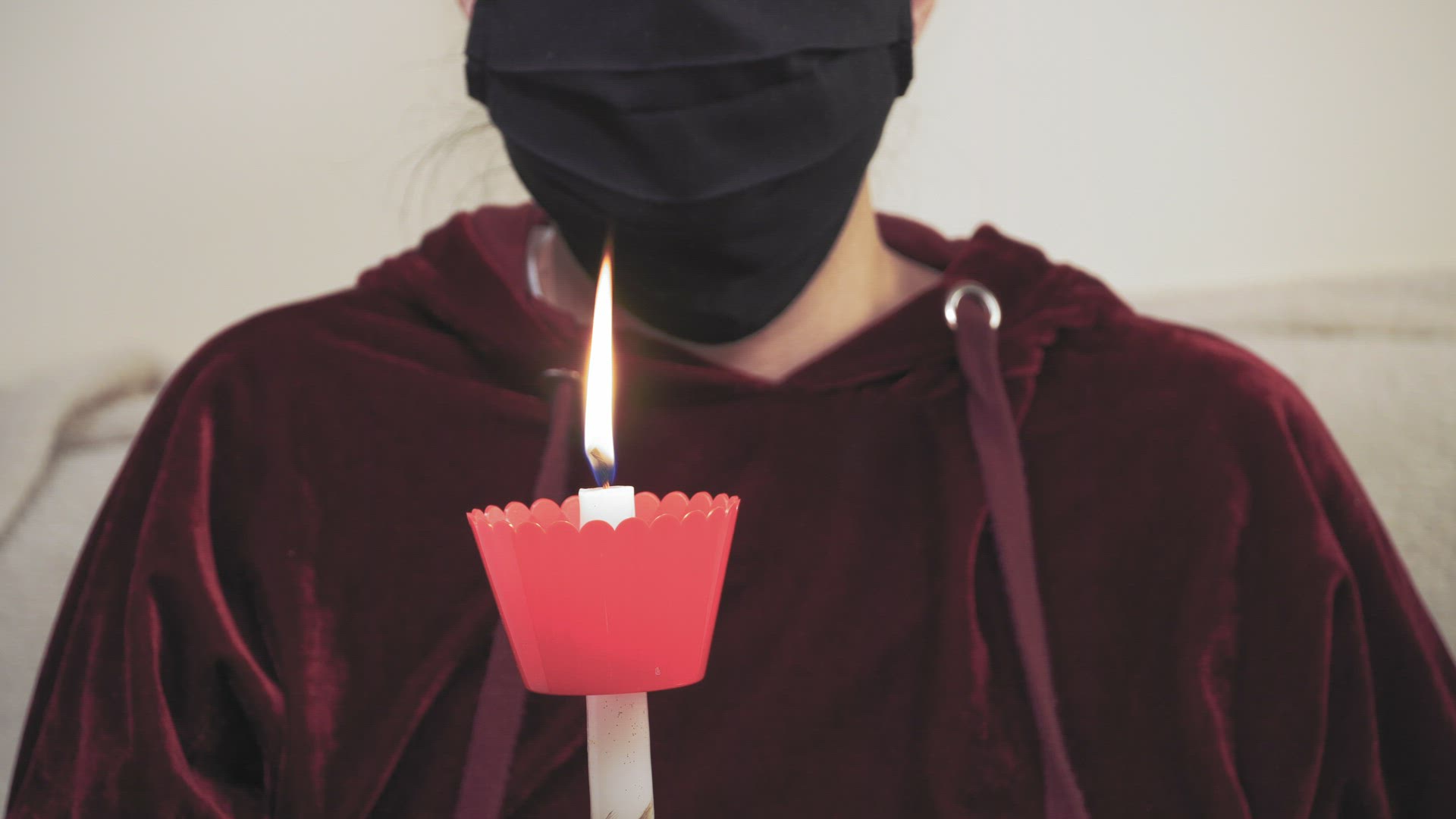 Person prays alone, moving Easter celebration glowing candle to the camera. 