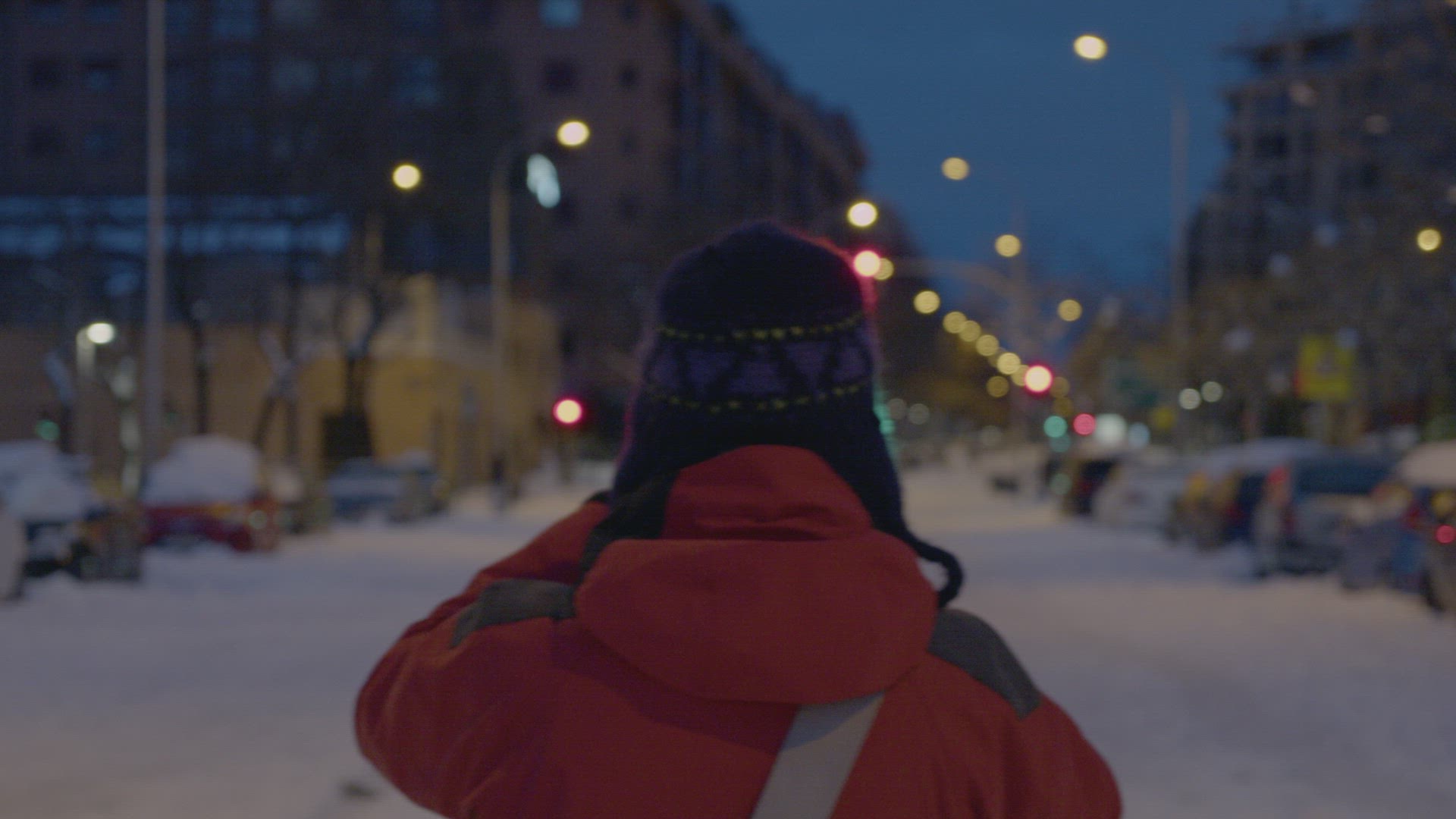 Tracking shot of a woman to the blue hour in the empty snowy city.