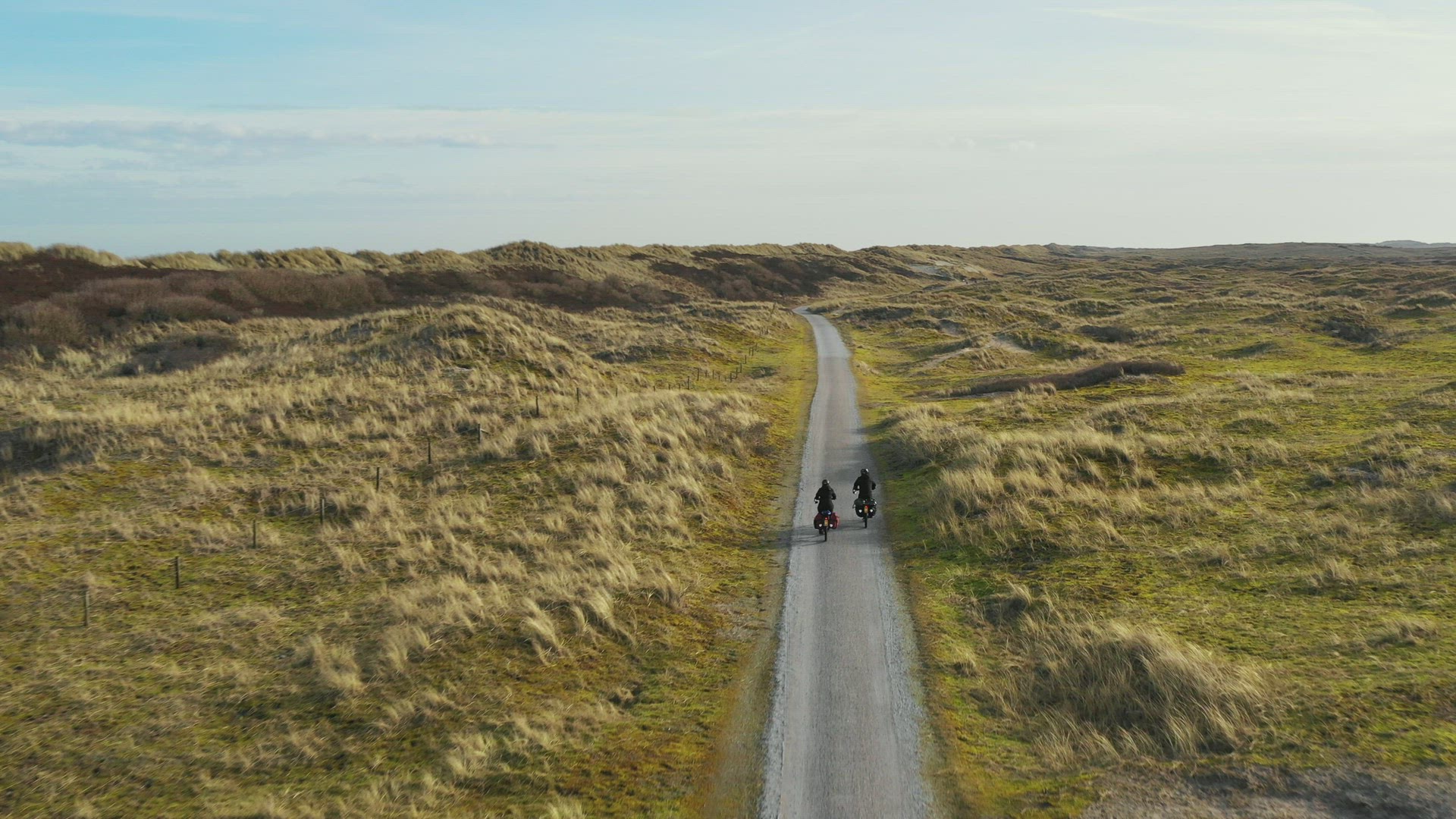 Man and woman riding bikes on dirt road, Nes, Friesland, Netherlands
