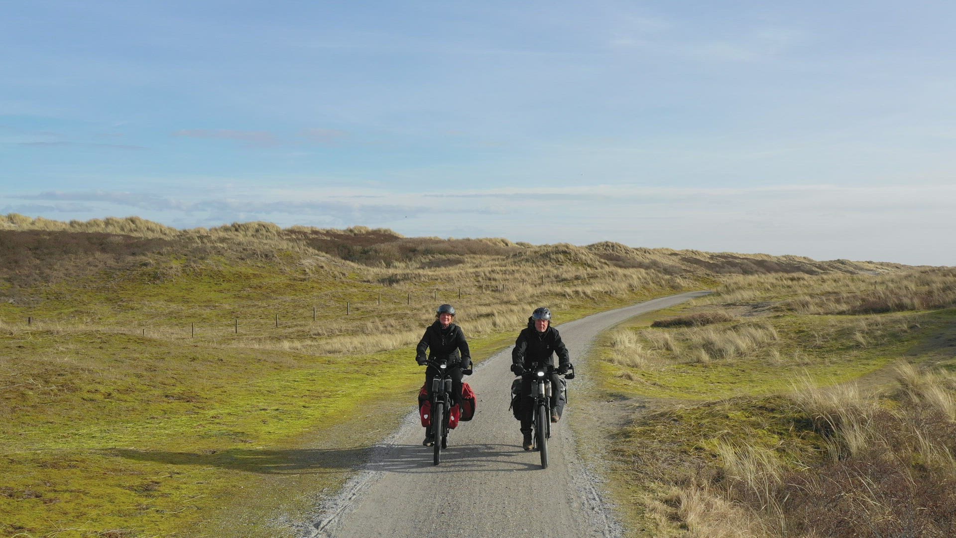 Man and woman riding bikes on dirt road, Nes, Friesland, Netherlands