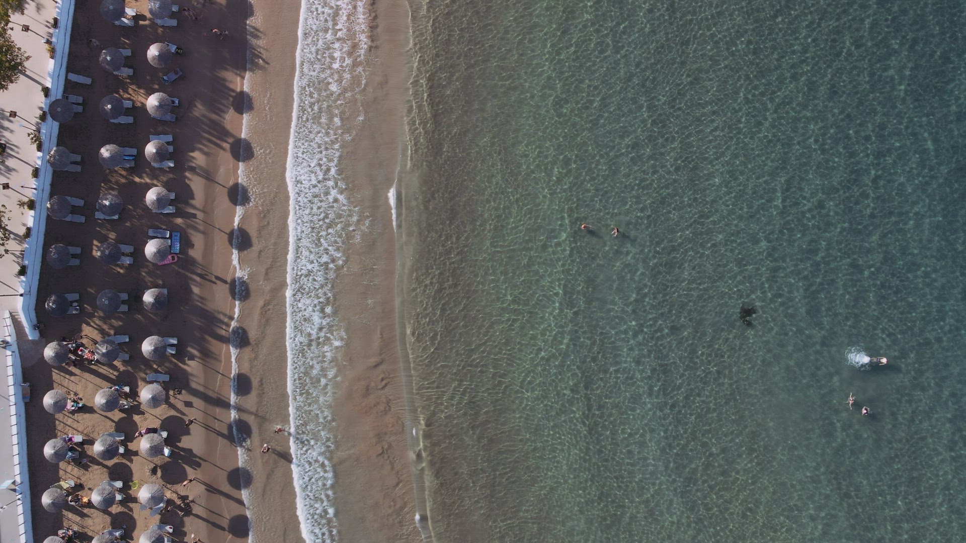 Mediterranean terrain Greek beach bar landscape drone still shot with unidentifiable bathers.
