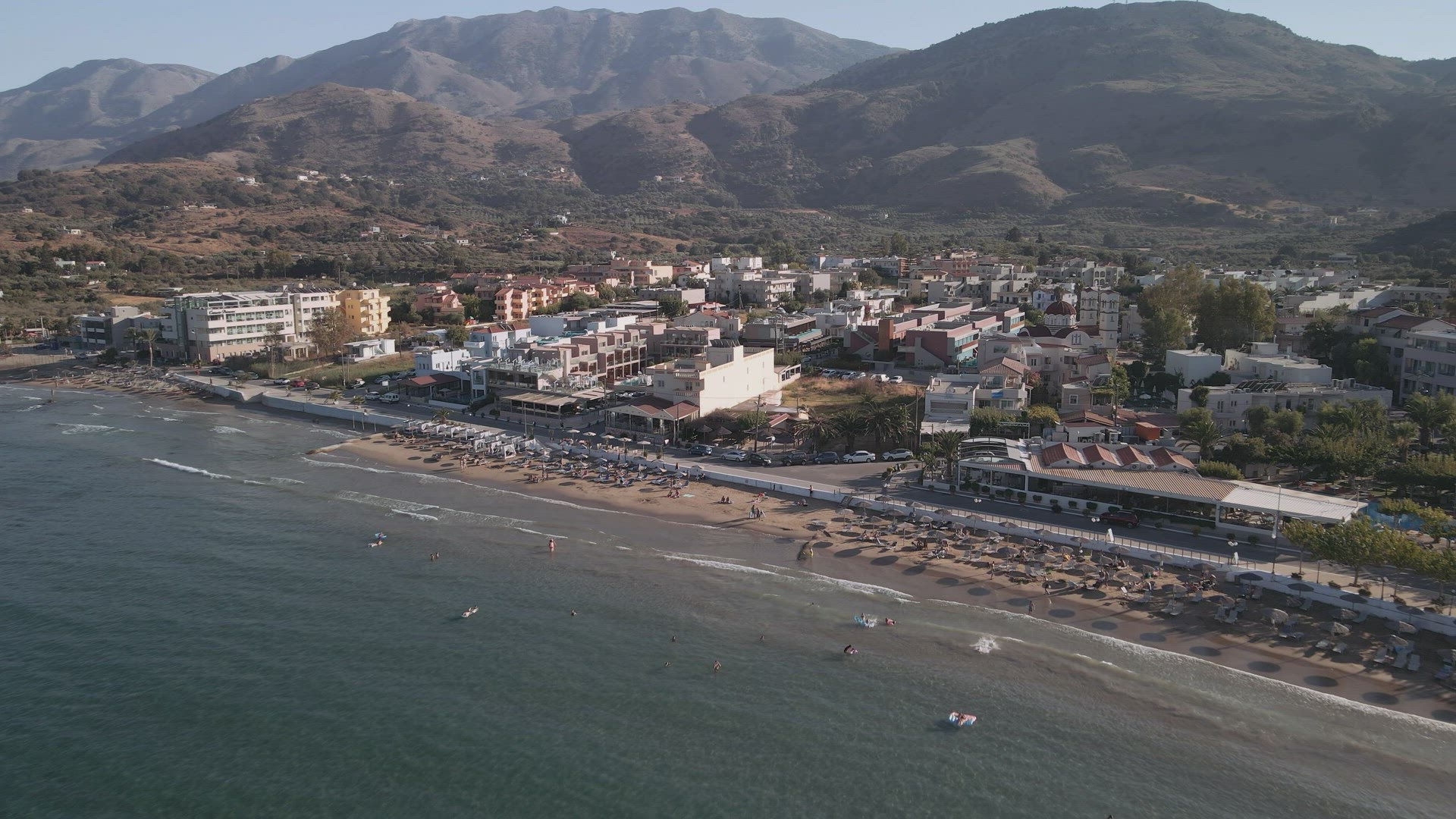 Mediterranean terrain Greek beach bar landscape drone shot with bathers.