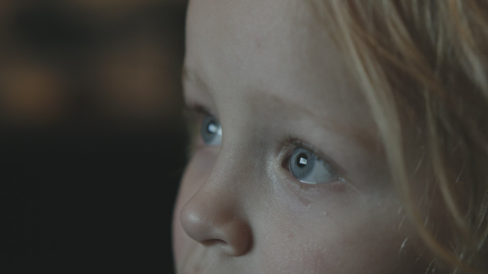Baby girl staring at TV screen being attracted with something curious