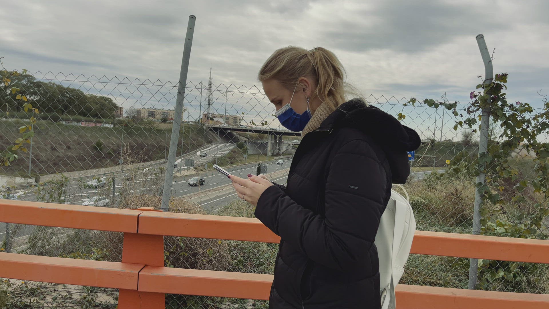 Woman with mobile crossing the overpass
