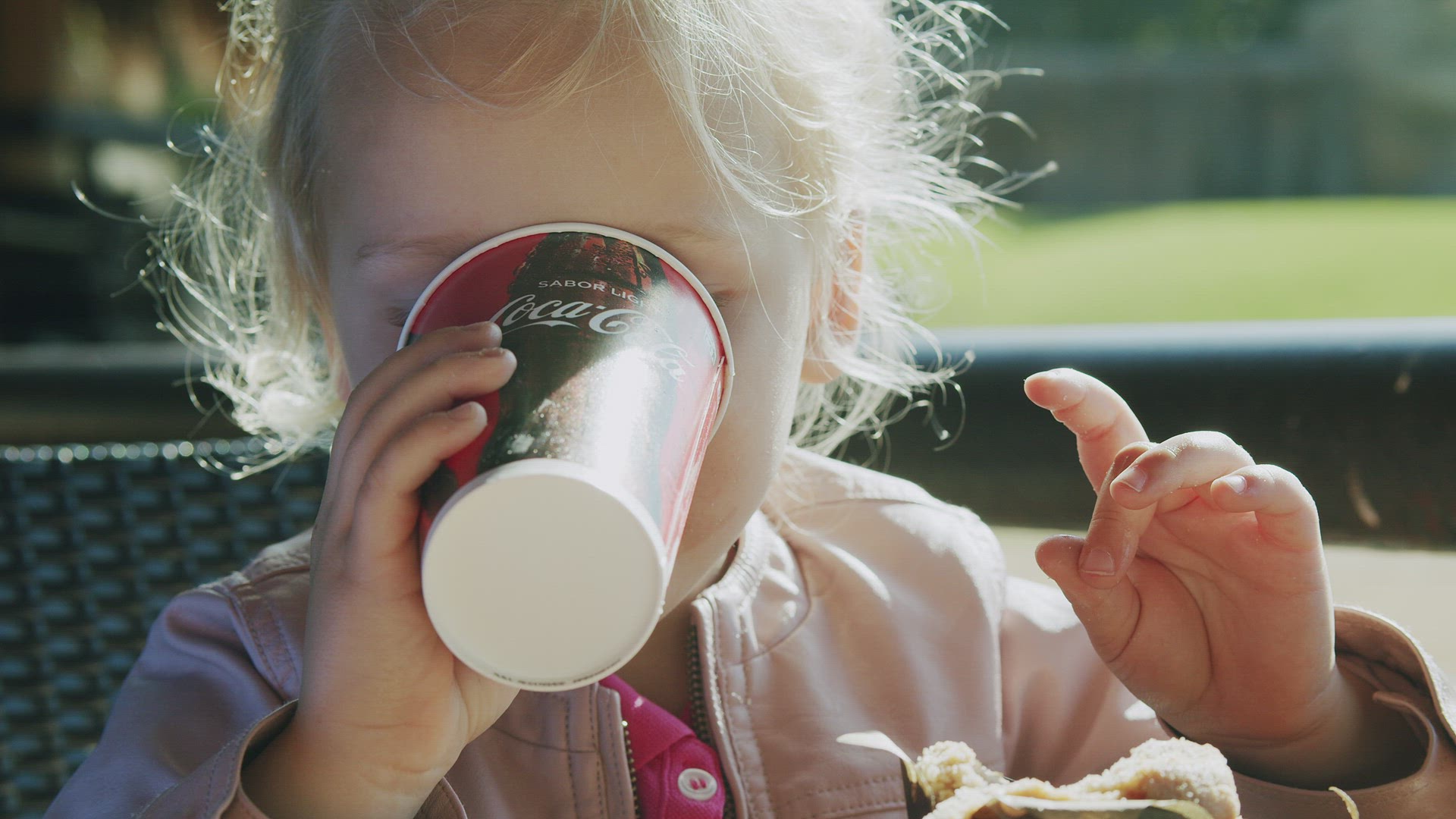 Little child finishing lunch with a cup of Coca Cola