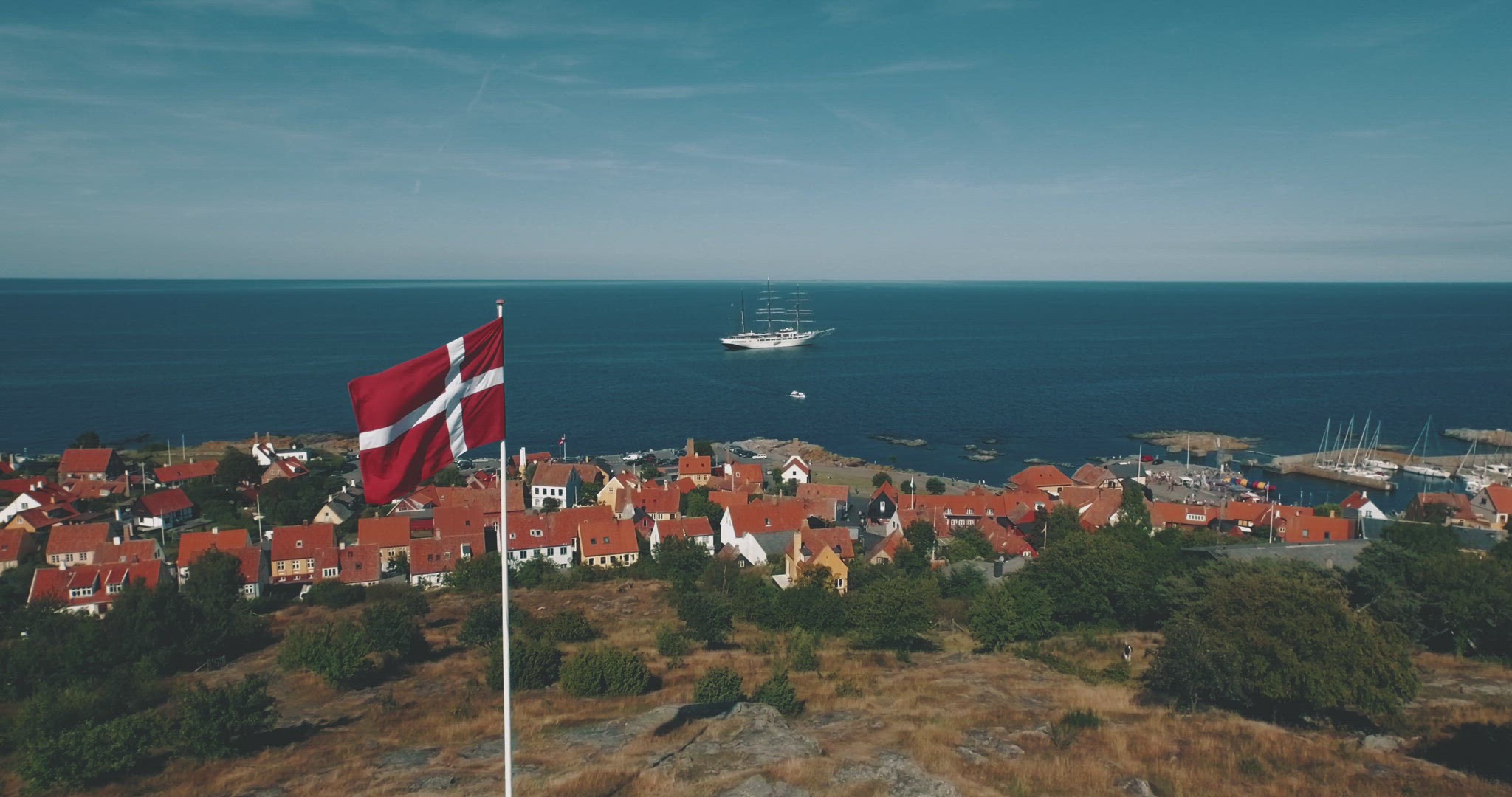 denmark flag flyby aerial sailboat at coastline harbour ocean summer 4k