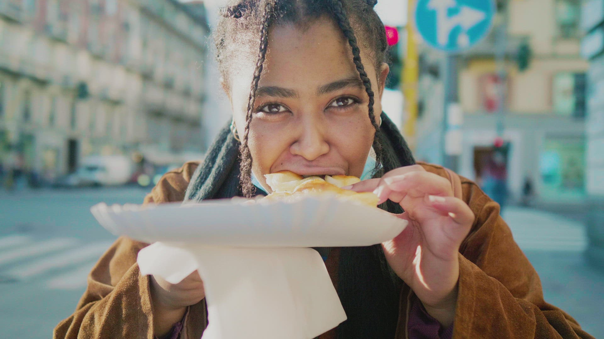 Portrait of young woman eating pastry outdoors, Italy
