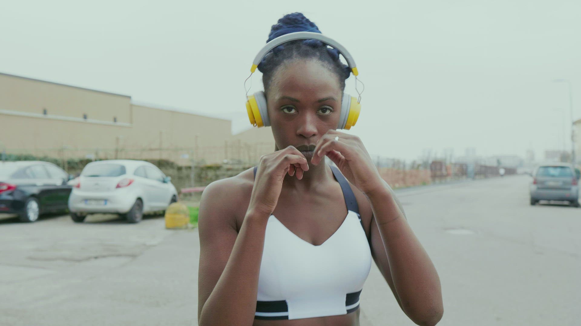 Young woman with headphones boxing in city, Milan, Italy