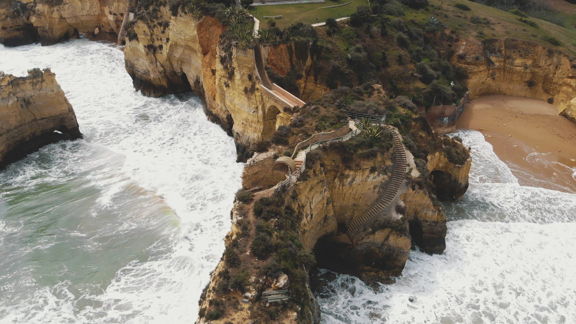 4k aerial drone footage of the rocky Ponta da Piedade limestone cliffs rising from the transparent o