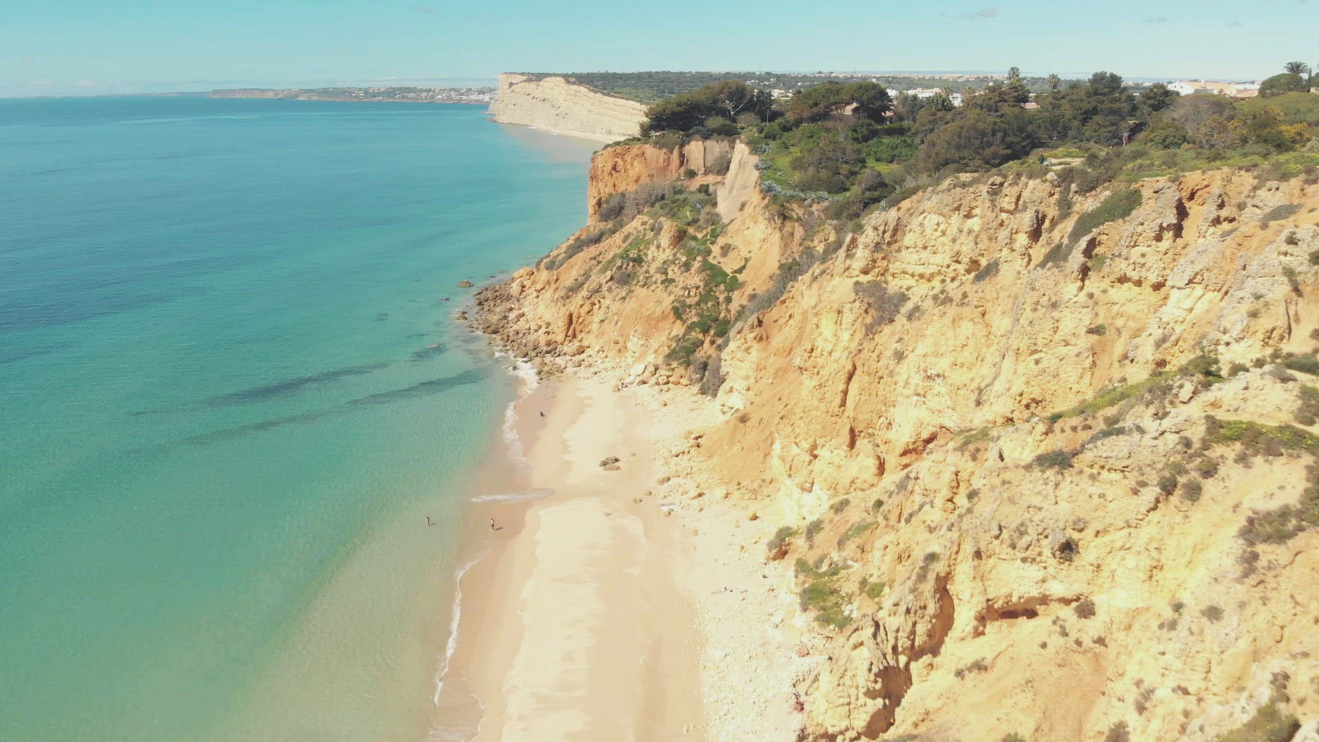 Golden sandy beach and yellow limestone scarps of Lagos, Algarve Coast, Portugal - Aerial fly-over t