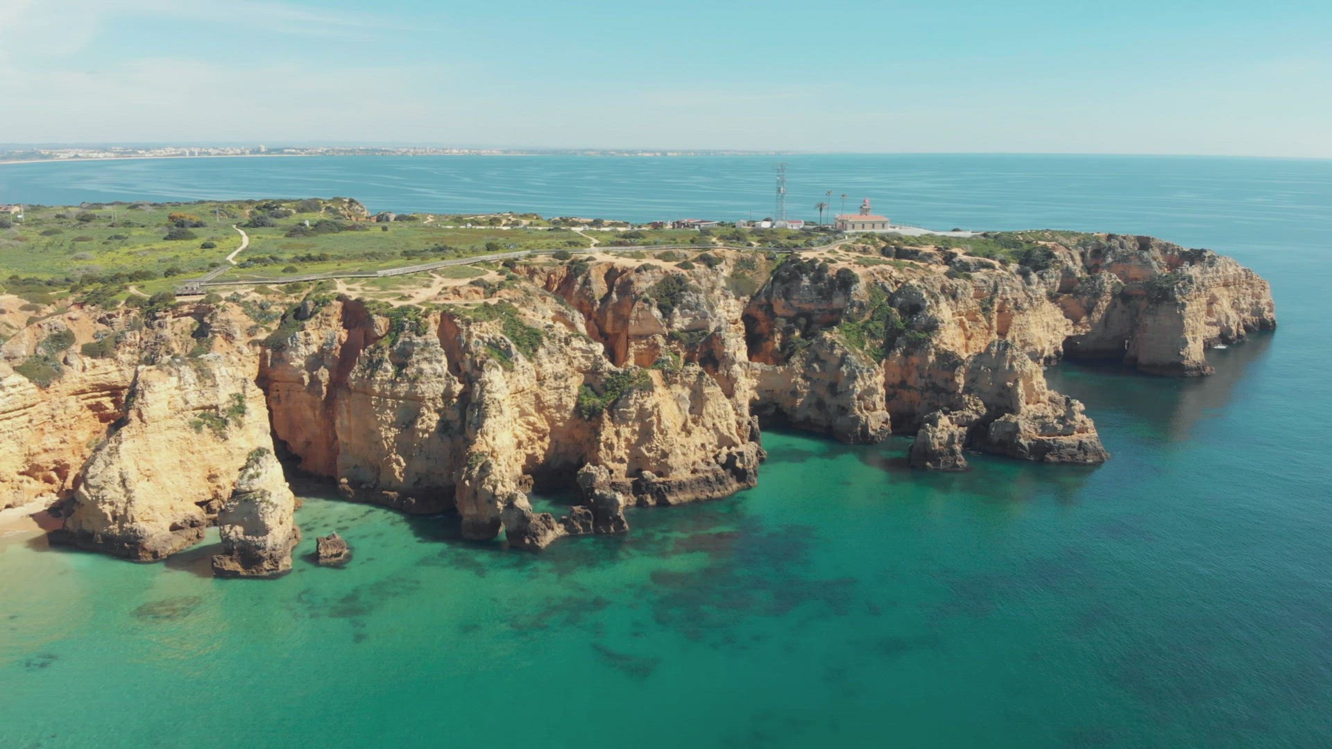 Fly over emerald Atlantic ocean off Lagos. Ponta da Piedade lighthouse overlooking cliffs