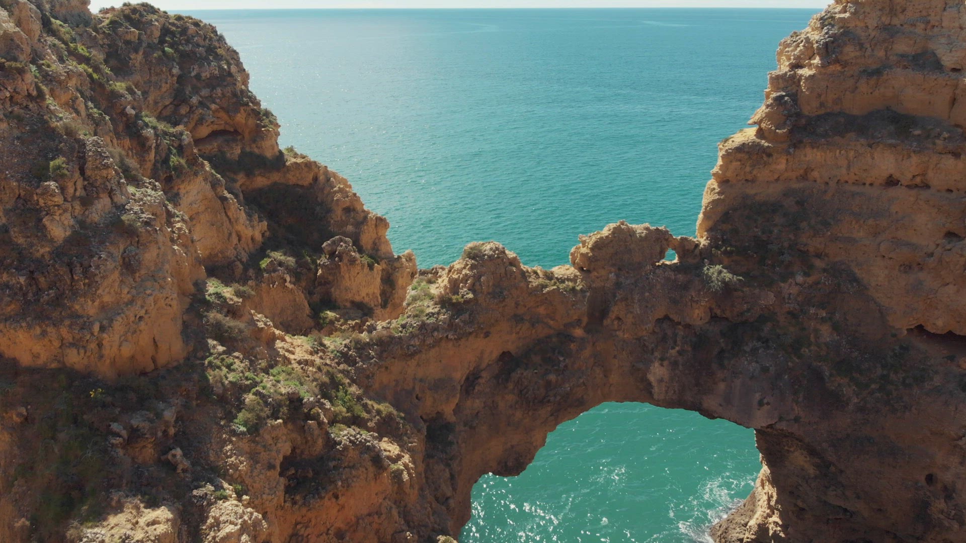 Fly-over 'Catedral' Stone Arch in Lagos, revealing Algarve Coastal sea, Portugal - Aerial low fly-ov