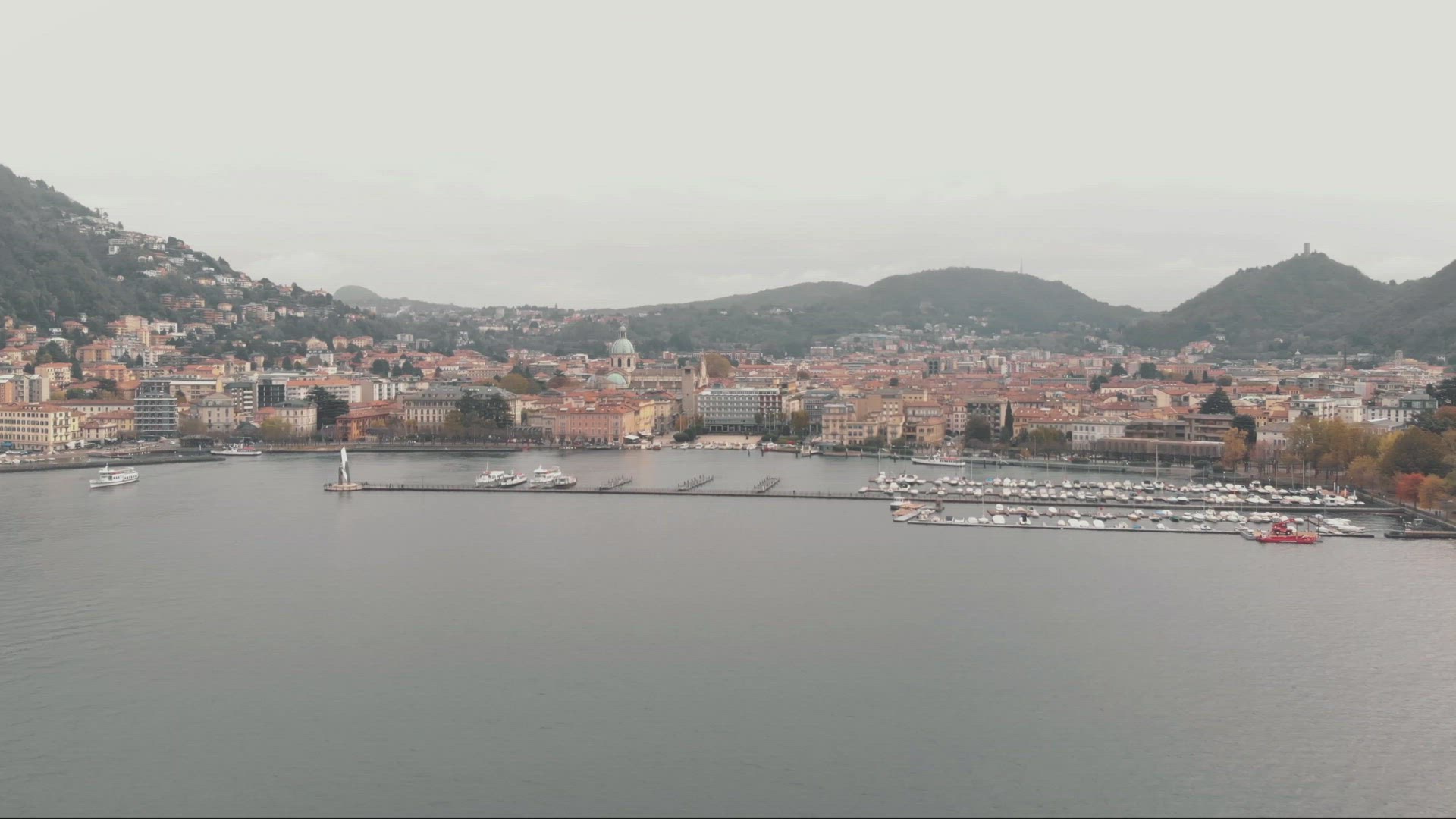 Aerial establisher of Como Lake , marina and city. Alps foothills in background	