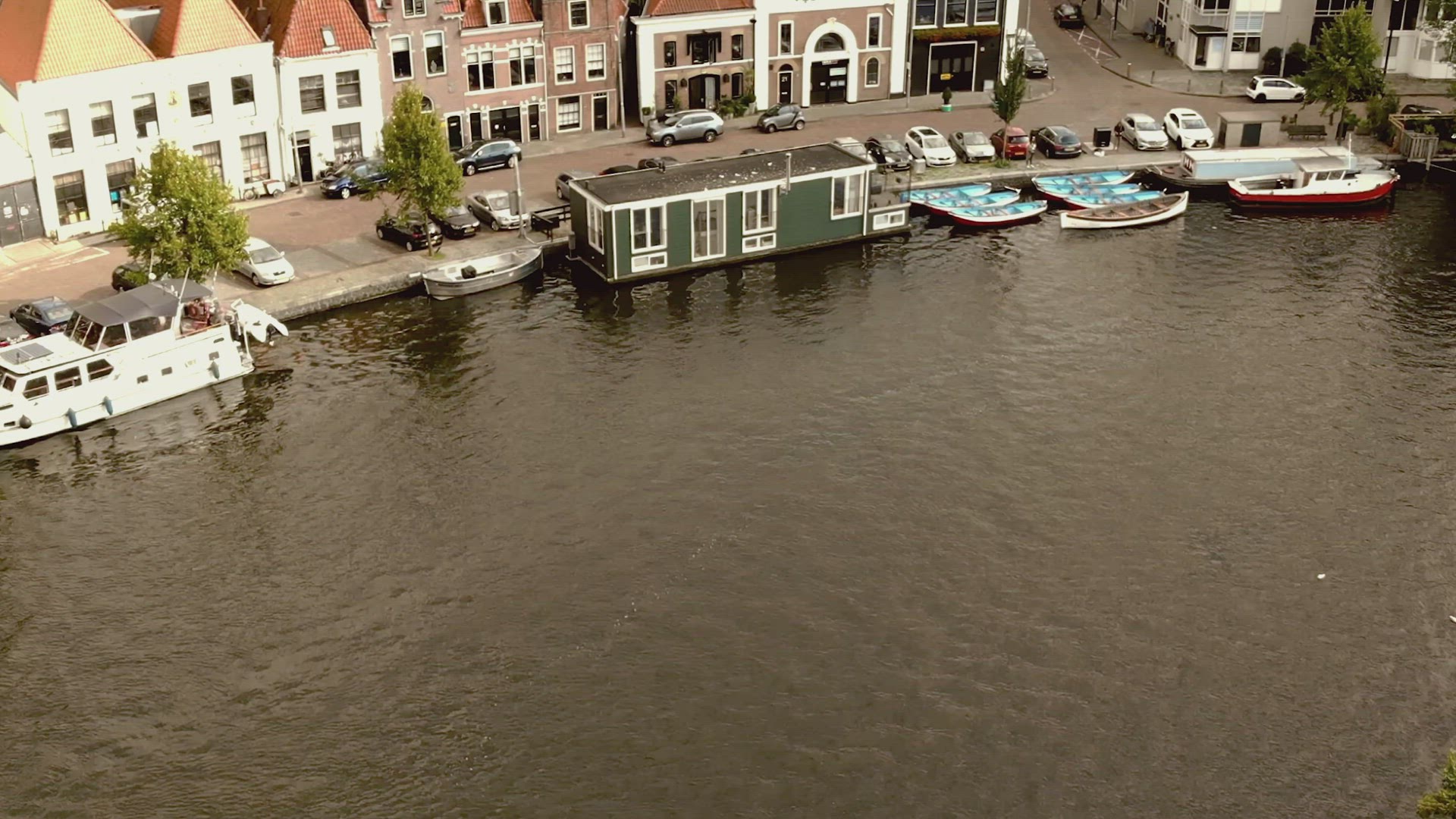 Haarlem canal with boats passing by moored Houseboats, Netherlands - Aerial