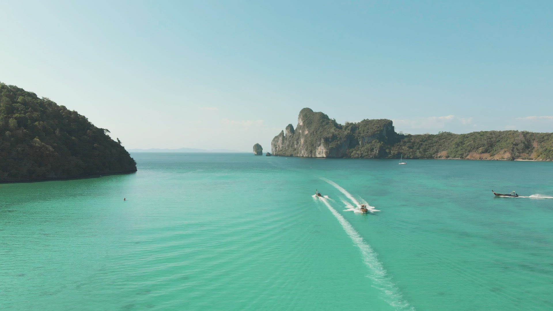 Pristine Loh Dalum Bay on a clear sunny day, crossed by motor boats in Ko Phi Phi Don Island Paradis