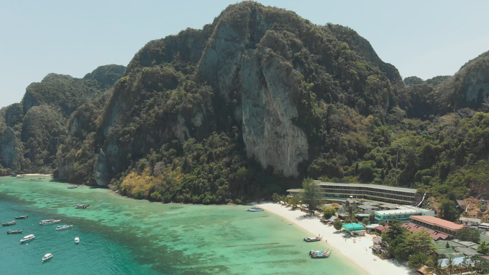 Towering limestone cliff restraining Tonsai Bay in Ko Phi Phi Don Island, Thailand - Aerial Fly-over