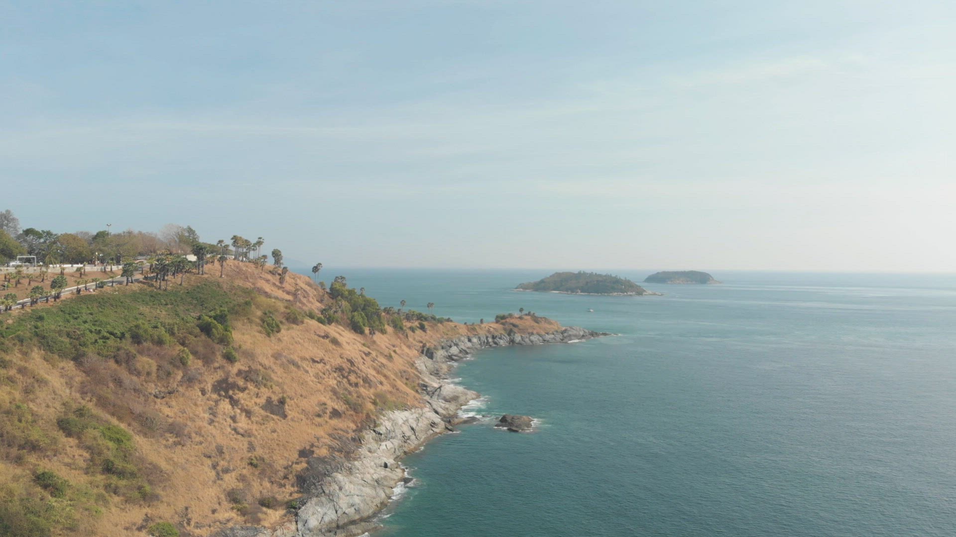 Steep barren hill connecting to Promthep Cape next to Yanui Beach in Phuket, Thailand - Aerial Panor