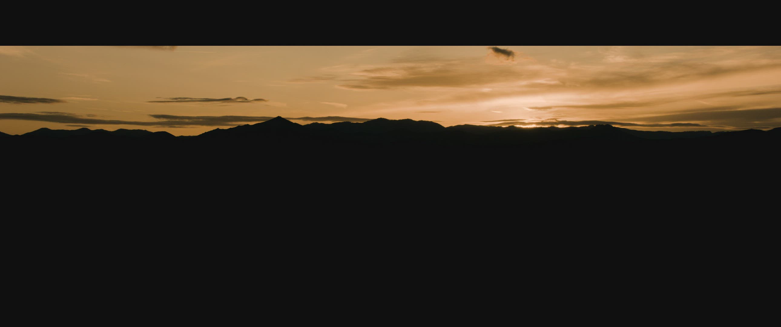 Dawn light over silhouetted desert mountains