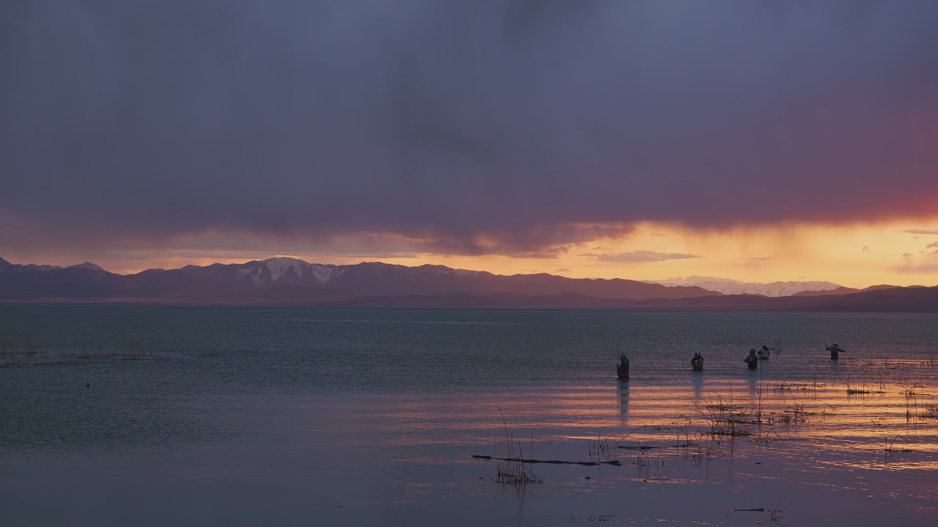 Fishermen lined up in Utah Lake during storm fishing during sunset