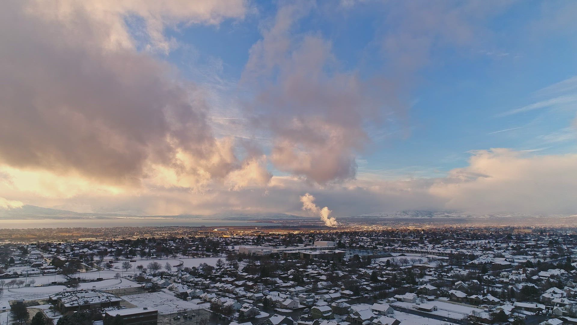 Flying over snow covered town as clouds glow in the sky