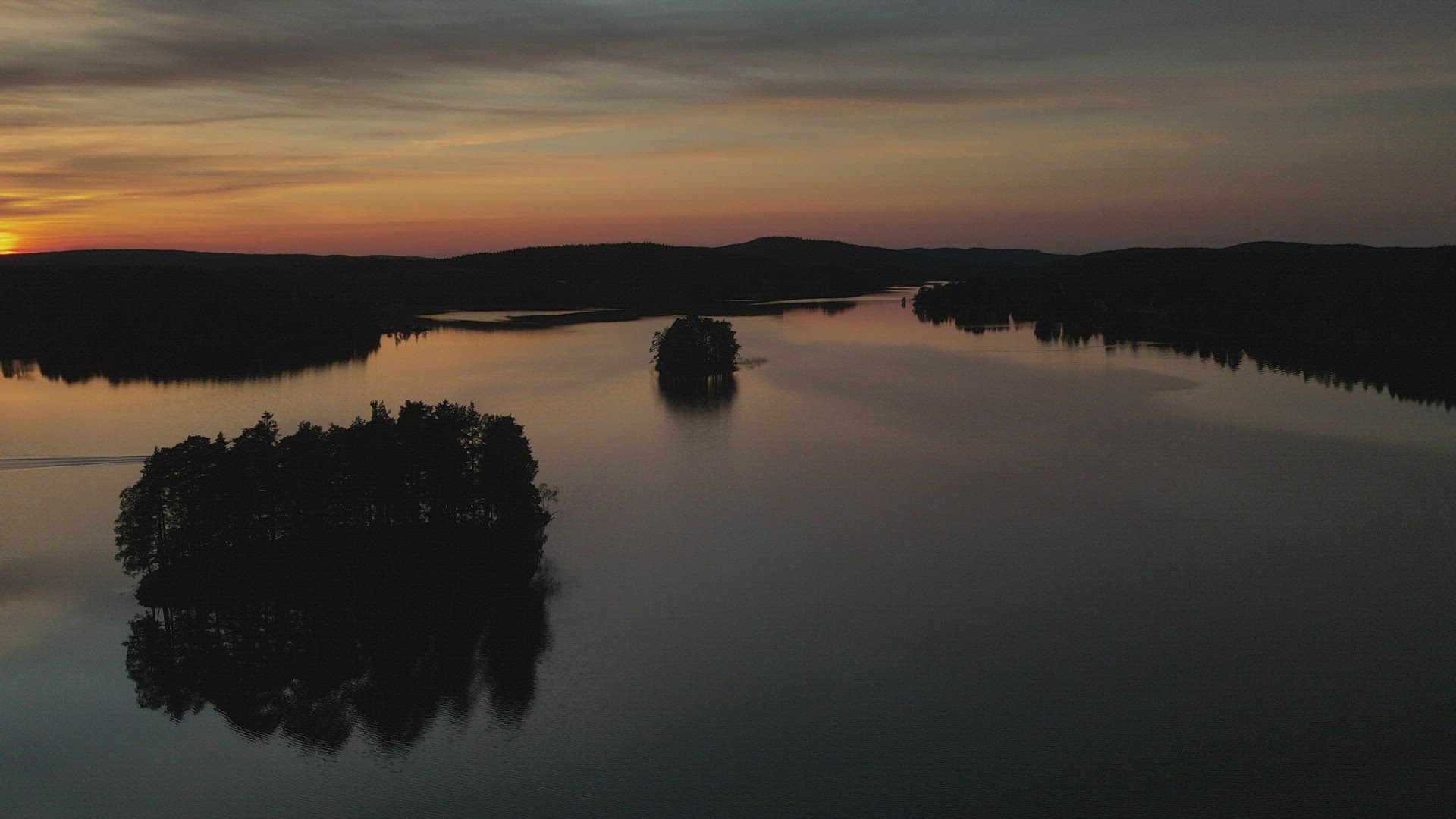 drone shot - aerial over gloassy lake - boat passing