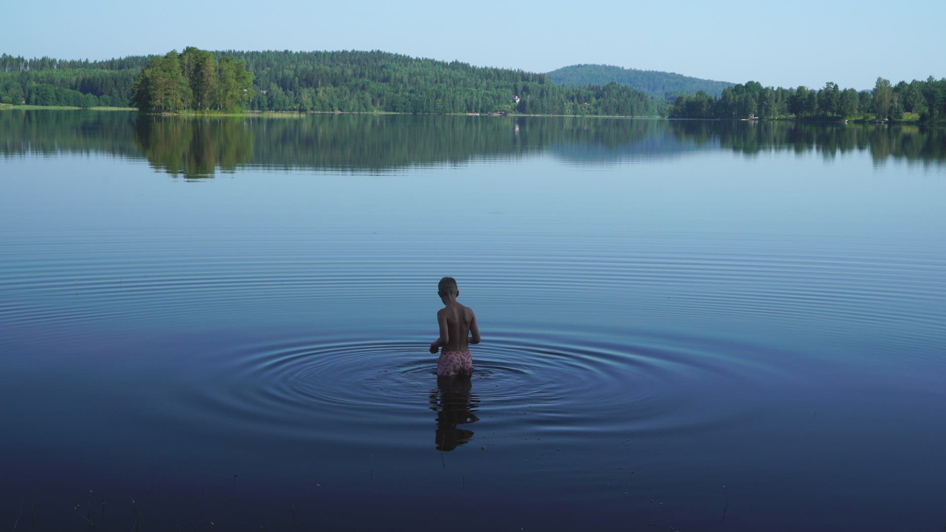 boy walking into water in lake
