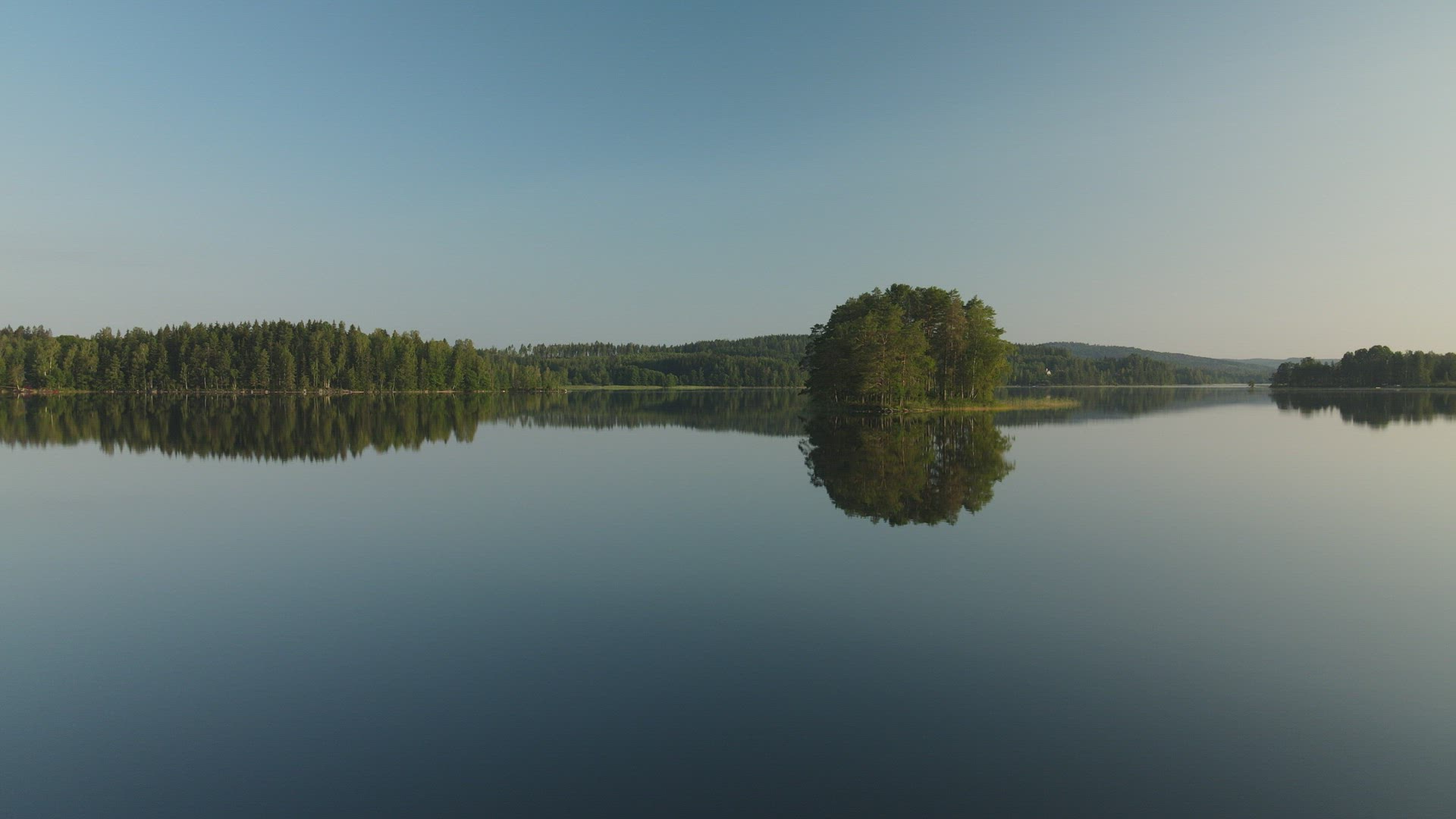 drone shot - flying over gloassy lake early in the morning