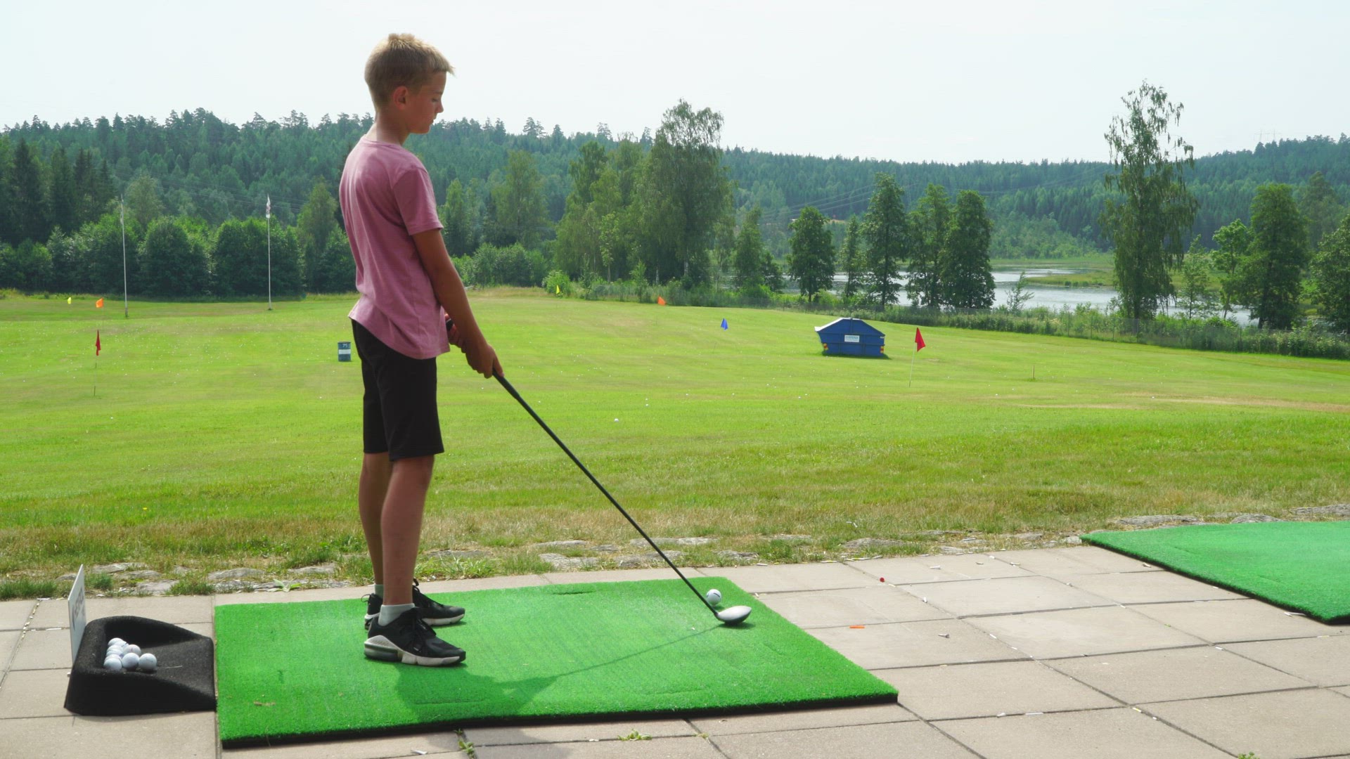boy practising golf on driving range - misses ball