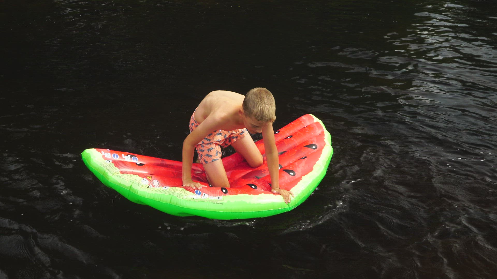 boy trying to stand on air mattress in water