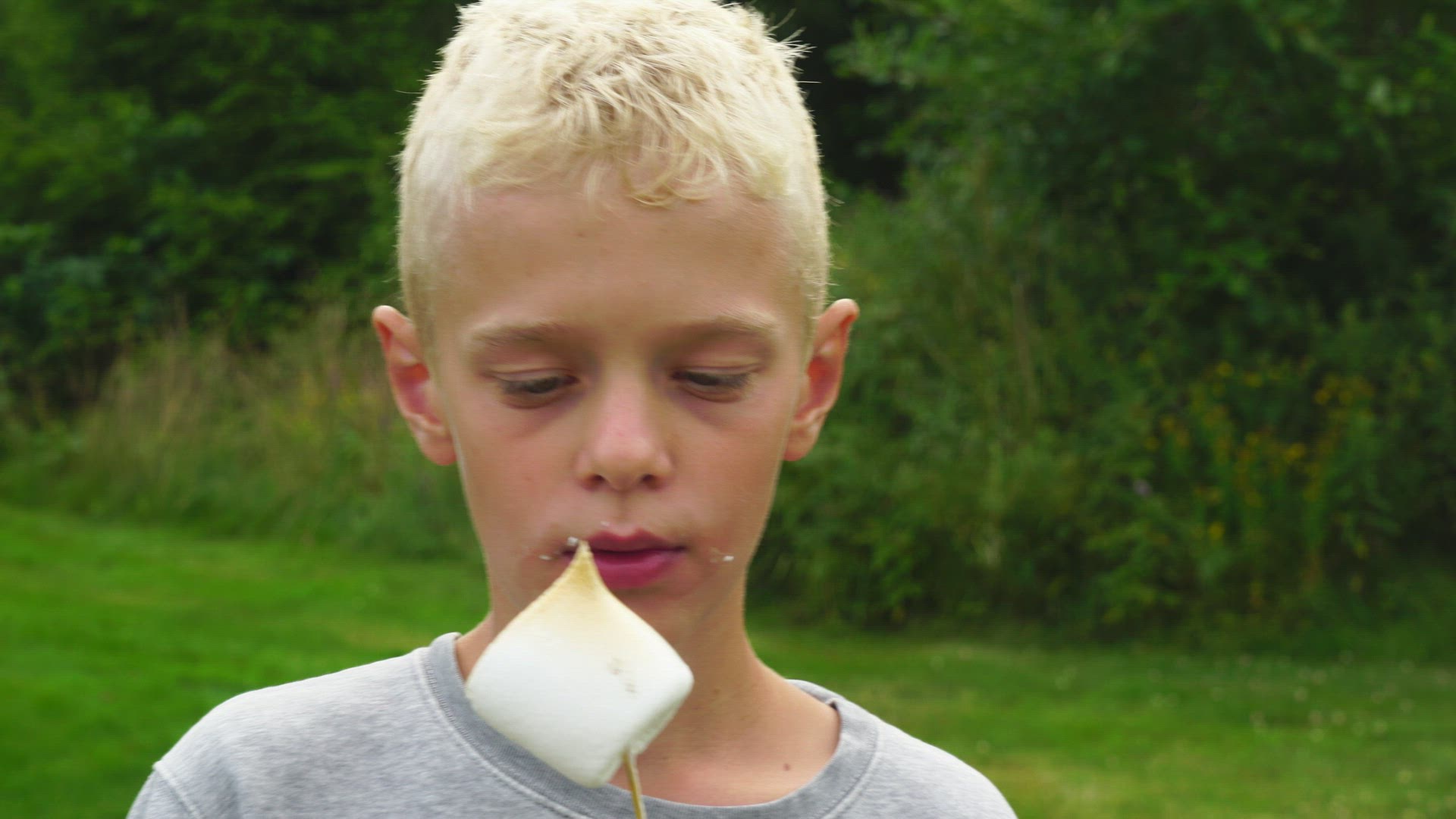 boy eats grilled marshmellow from stick