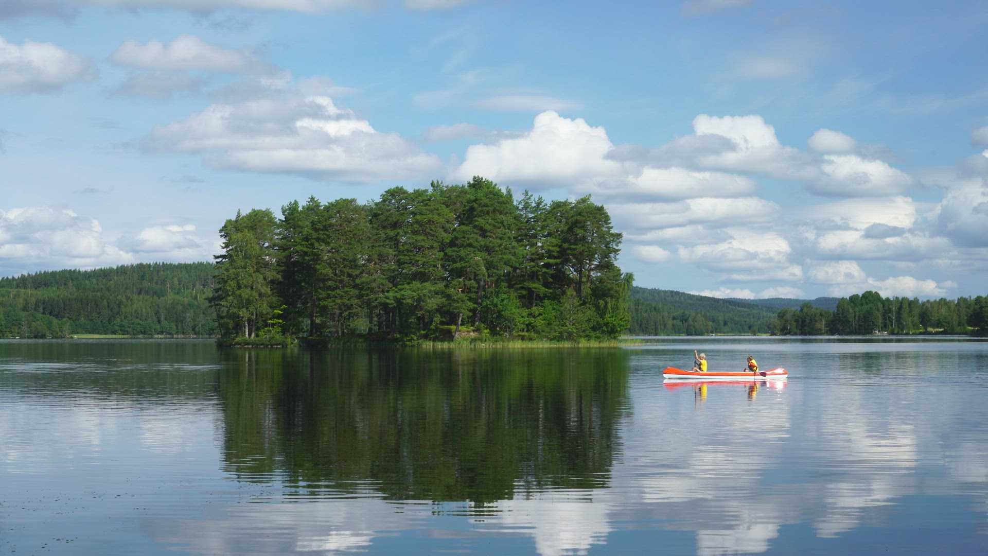 two boys paddling canoe on a mirror lake