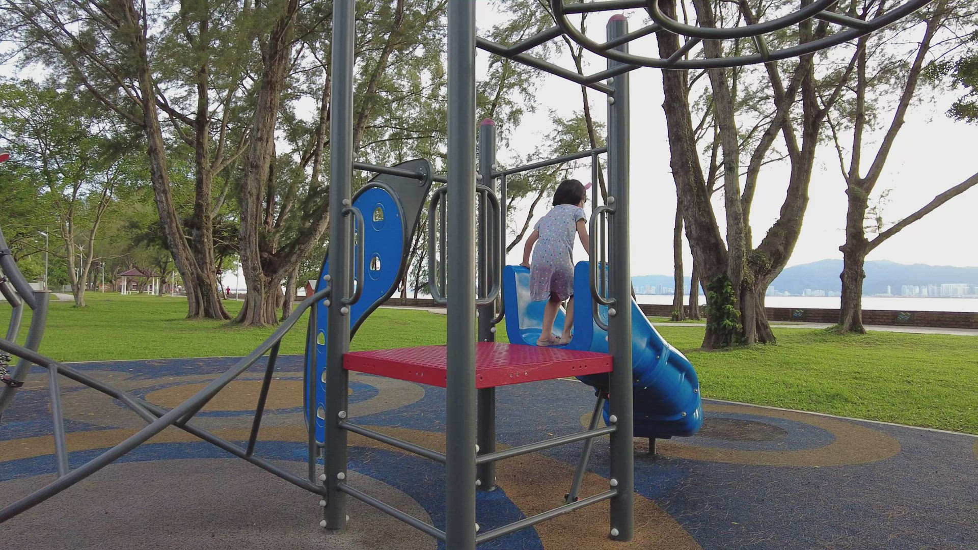 Back view of little girl play slider at playground