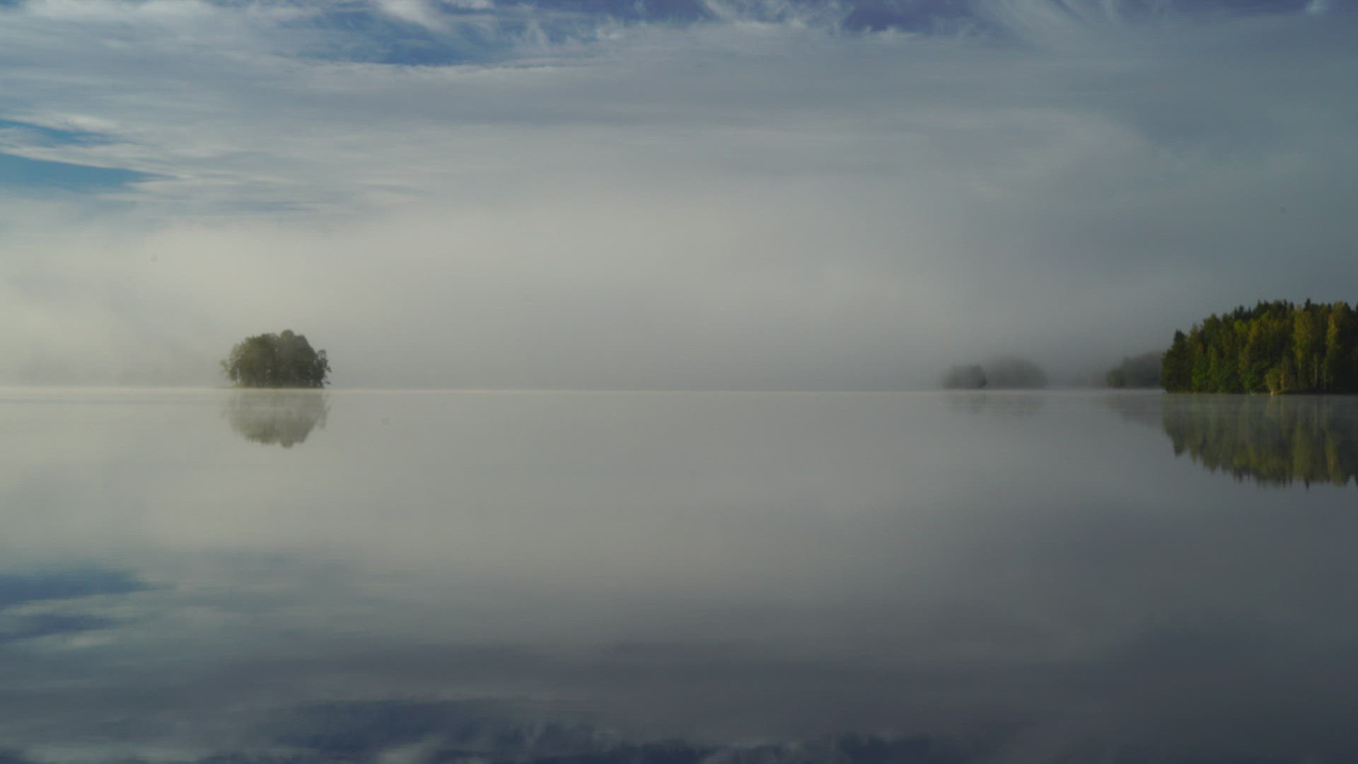 view over gloassy lake at dawn - mist - fog over lake and forests