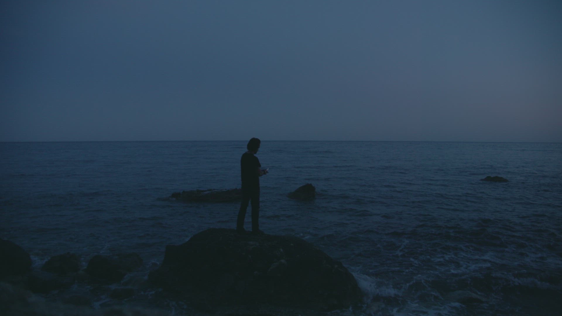 Man lights flare at dusk on the beach