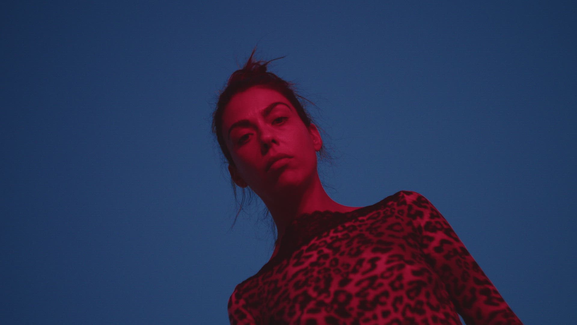 Young woman illuminated in red over blue sky