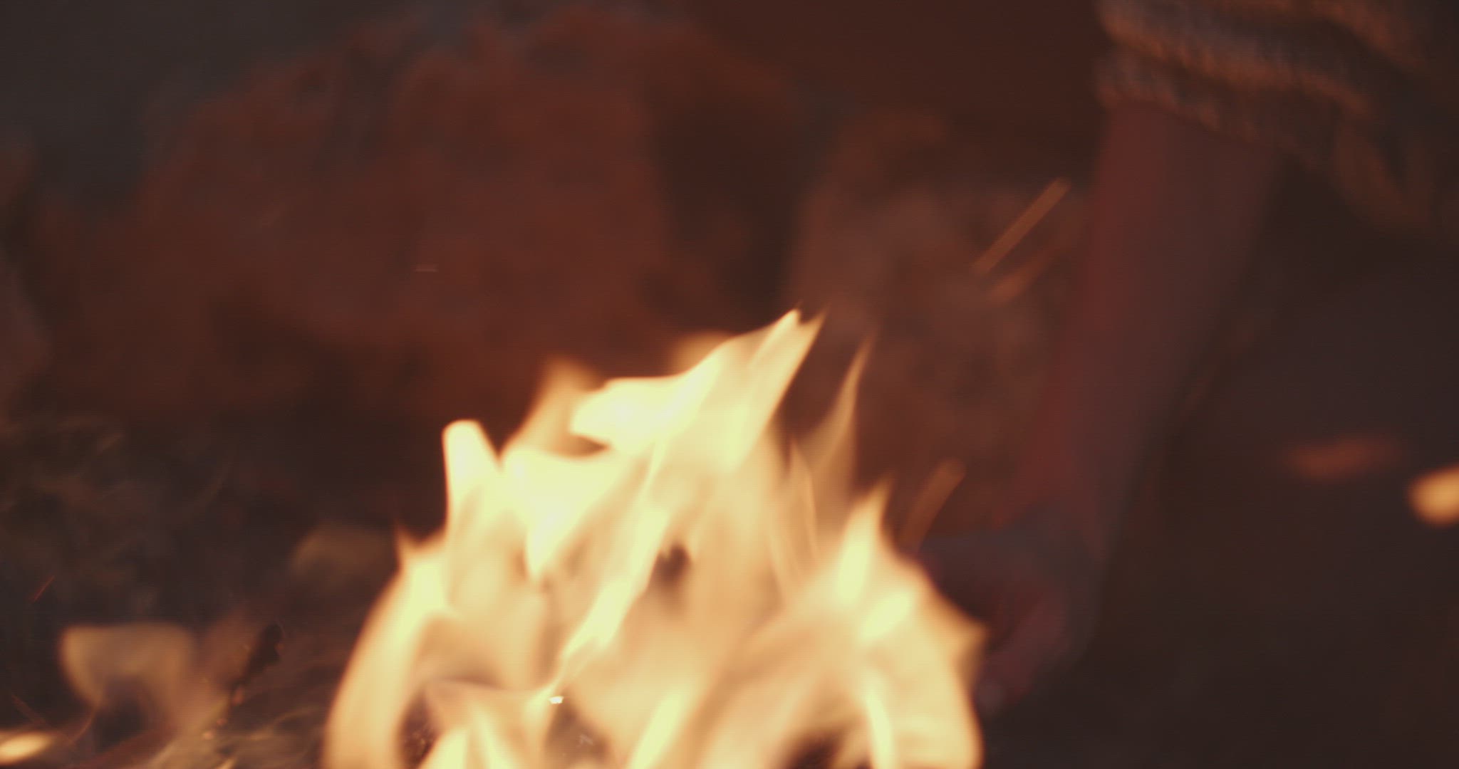Woman touches the fire and looks at camera