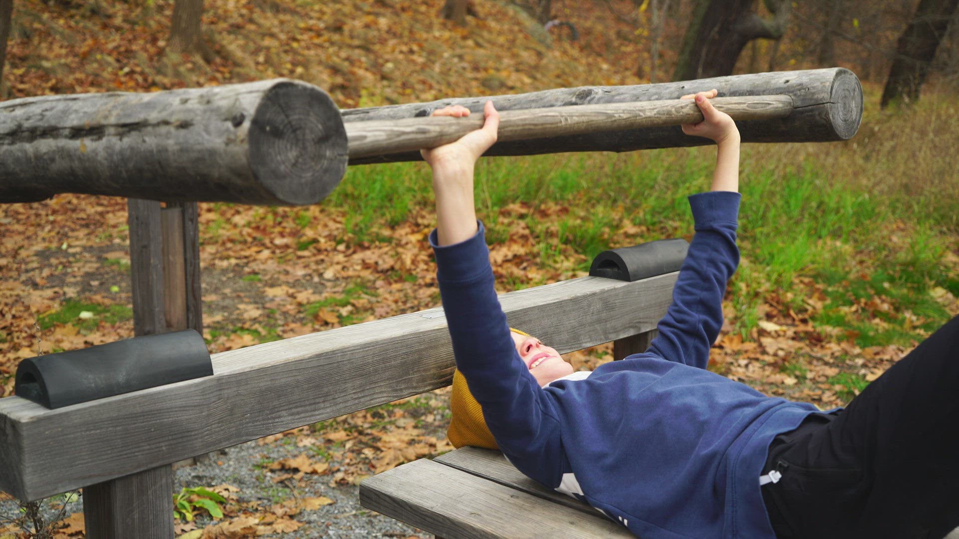 boy in outdoor gym - lifts weights lying on bench