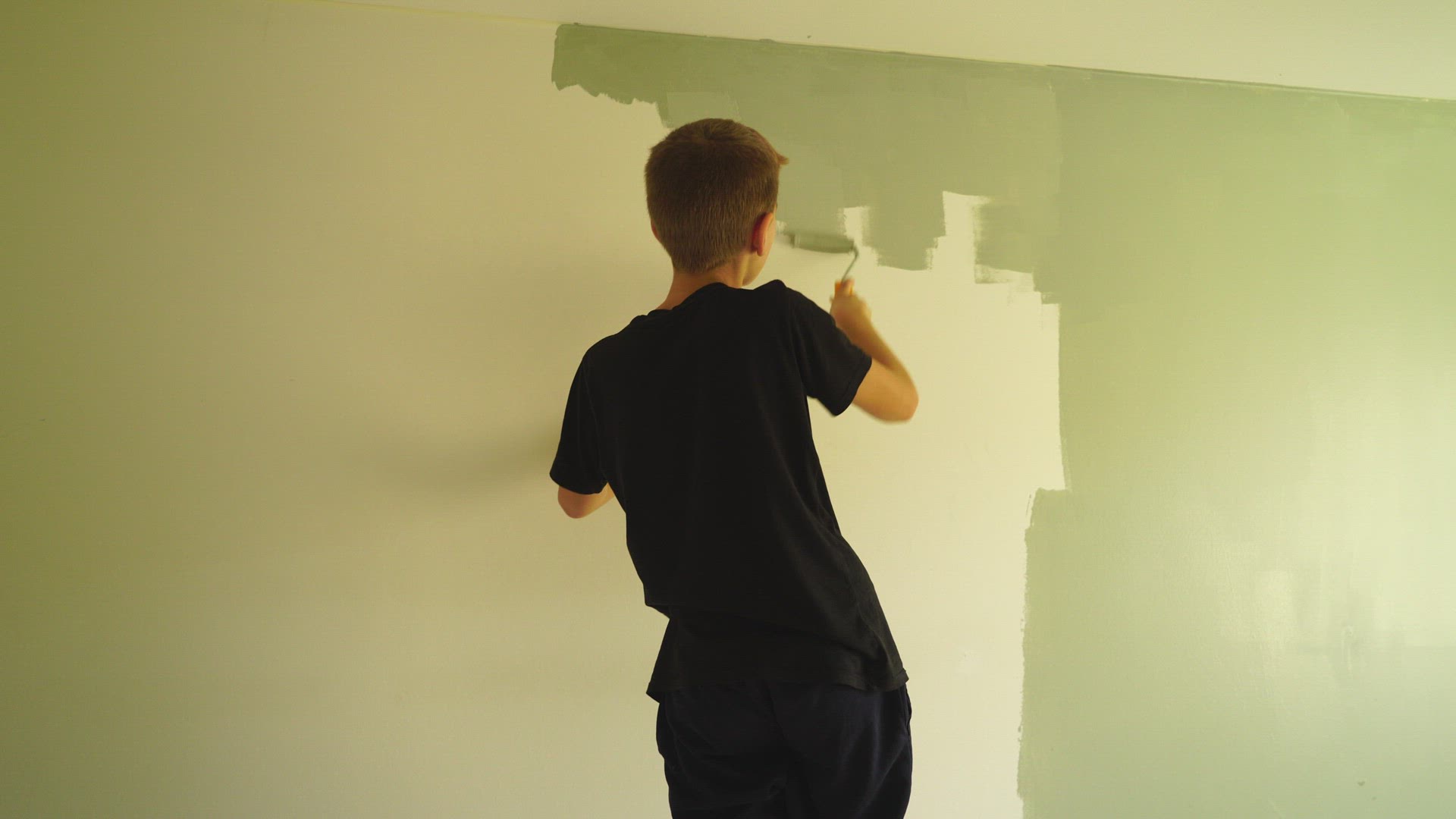 boy paints a wall - green colour