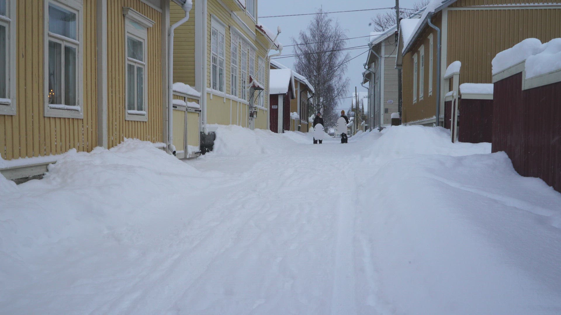 boys sliding down snowy city street on toboggans