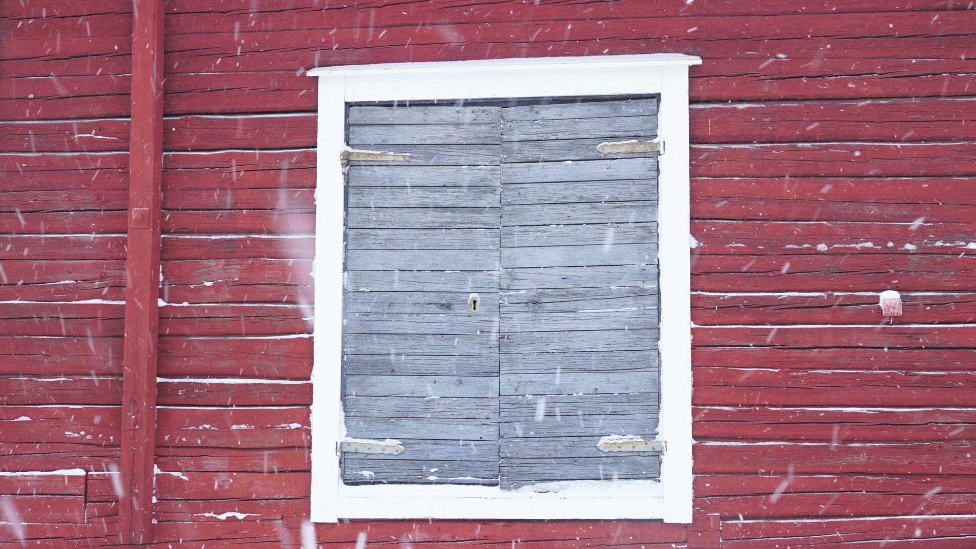 red wall with grey door in snowfall