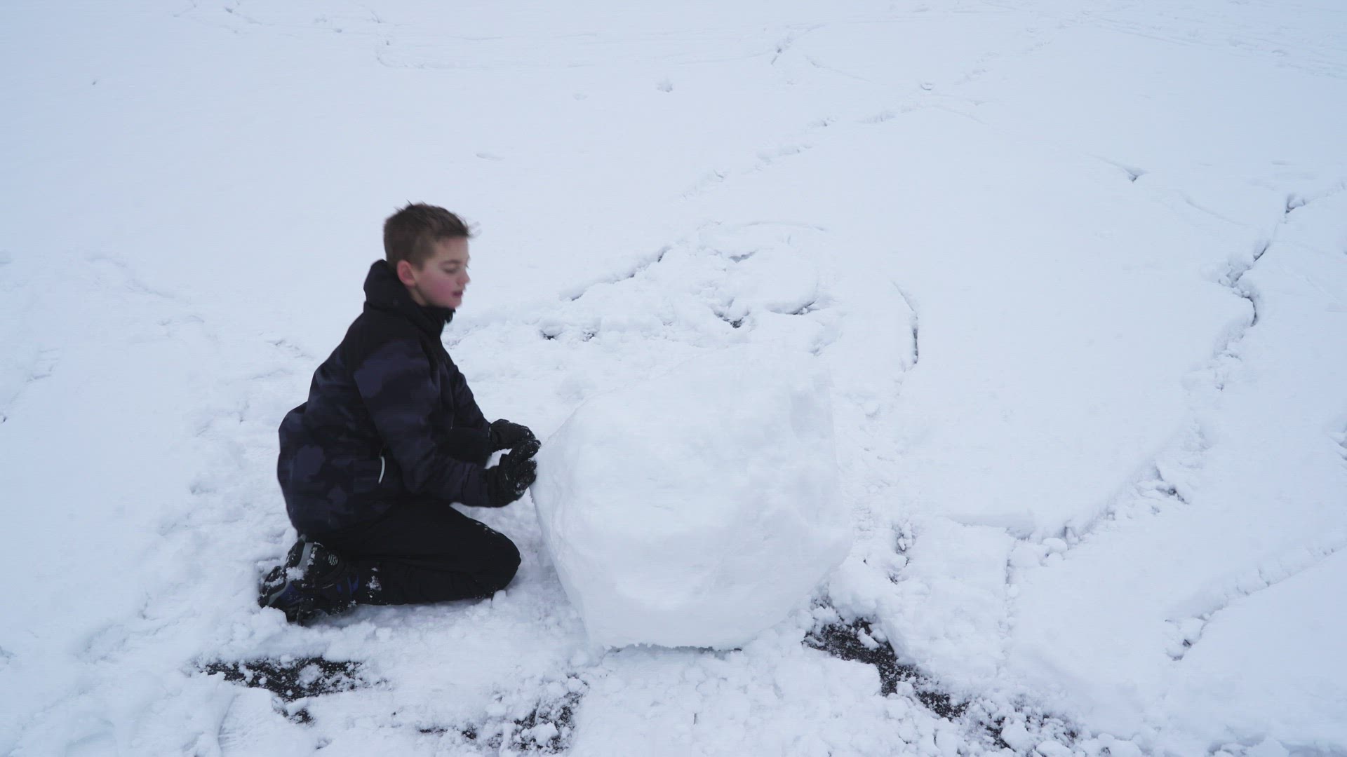 boy sitting on ice - rolling big snowball