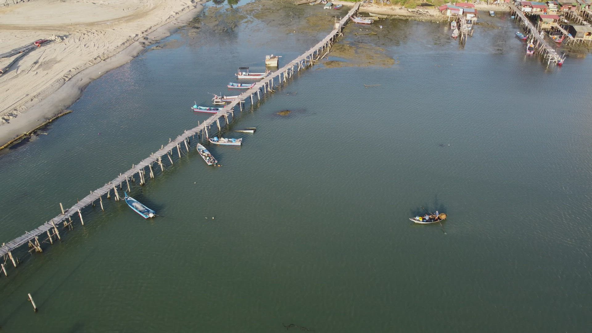 Aerial view fishermen row boat toward wooden jetty