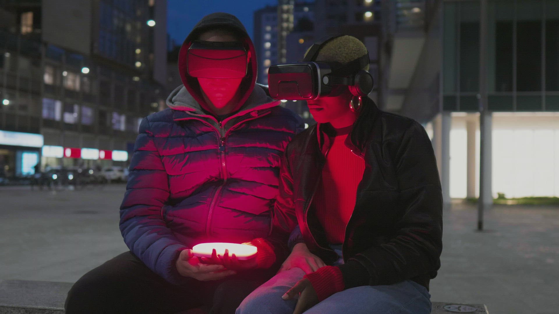 Man and woman with VR goggles and smart phone in city at night