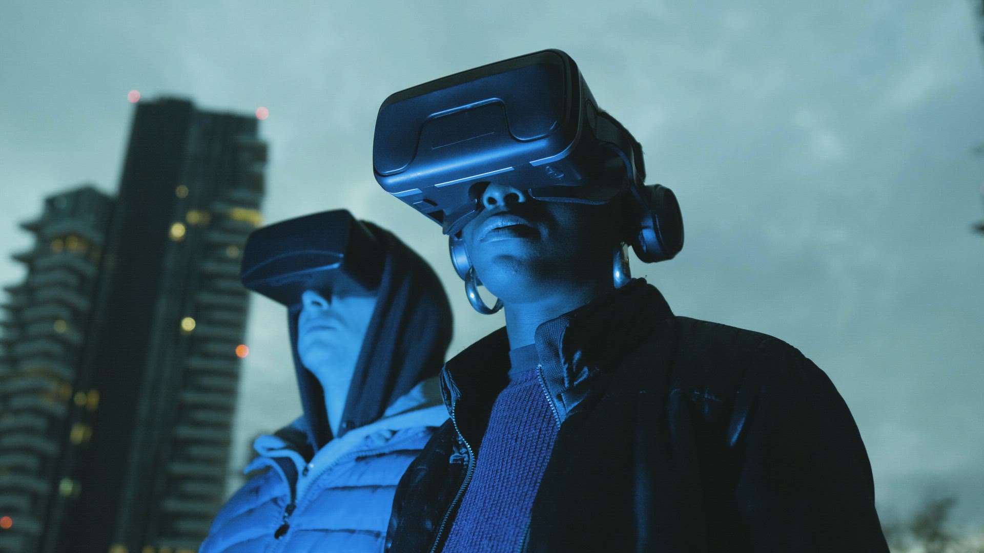 Man and woman with VR goggles in city at night