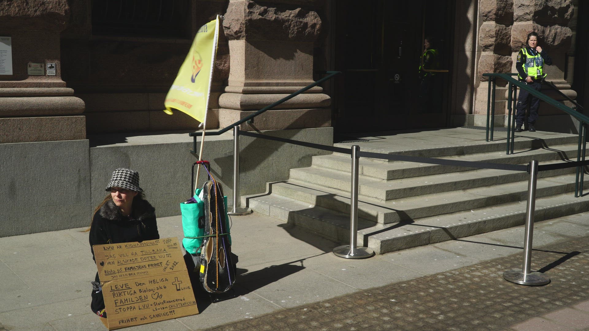woman protesting outside swedish parliament entrance - placard